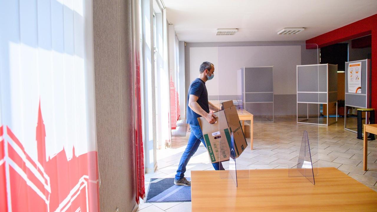 Ein Mitarbeiter der Stadt Magdeburg trägt einen Karton in ein Wahllokal.

