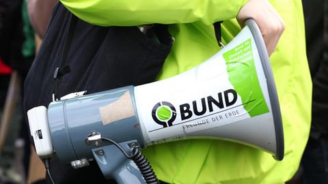 Ein Demonstrant hält ein Megafon mit einem Aufkleber mit der der Ausfschrift "BUND" - für Bund für Umwelt und Naturschutz Deutschland - bei einer Demonstration