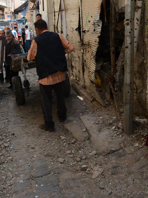 Eine Frau und ein Kind schauen in der hnistorischen Altstadt von Diyarbakir auf eine Gruppe von Männern bei Aufräumarbeiten.