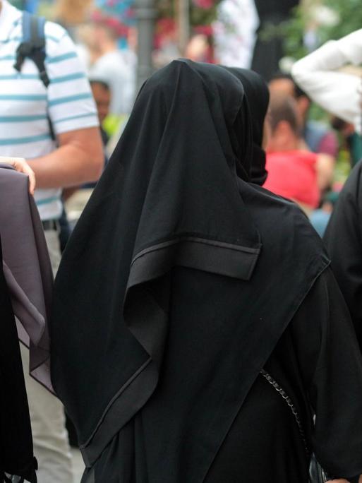 Arabische Muslima mit Burkas spazieren in der Innenstadt von München.