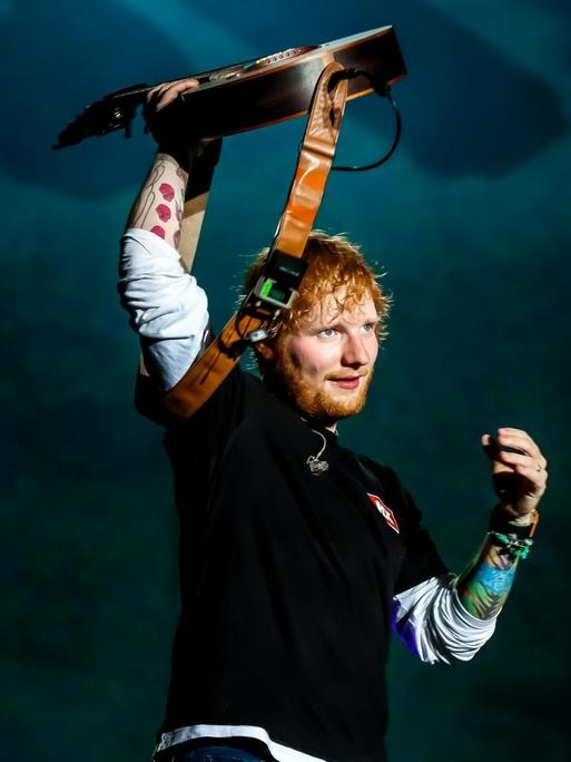 Der Singer und Songwriter Ed Sheeran steht beim Sziget Festival in Budapest auf der Bühne und reckt eine Gitarre in die Höhe.