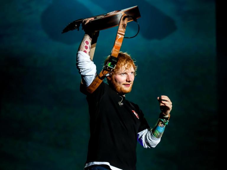 Der Singer und Songwriter Ed Sheeran steht beim Sziget Festival in Budapest auf der Bühne und reckt eine Gitarre in die Höhe.