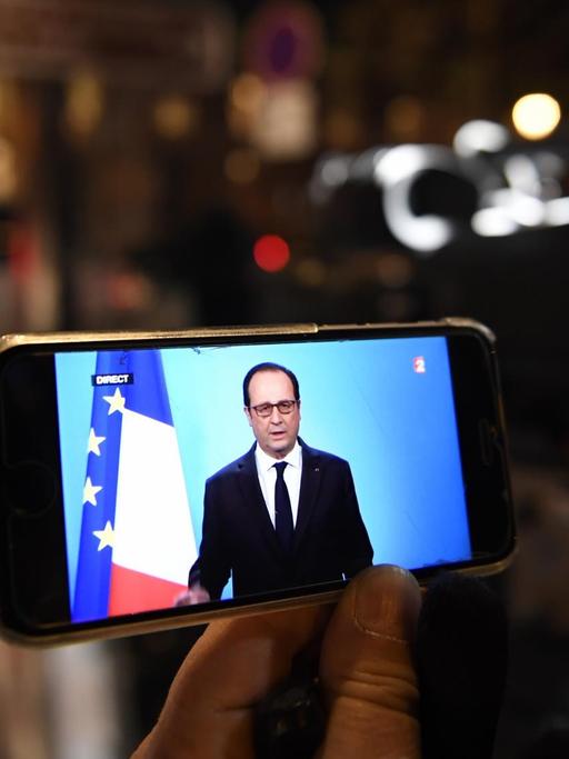 Die Rede von Frankreichs Präsident Hollande ist auf einem Handydisplay zu sehen.