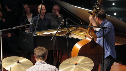 Ein Pianist, ein Kontrabassist und ein Schlagzeuger spielen auf der Bühne vor Publikum