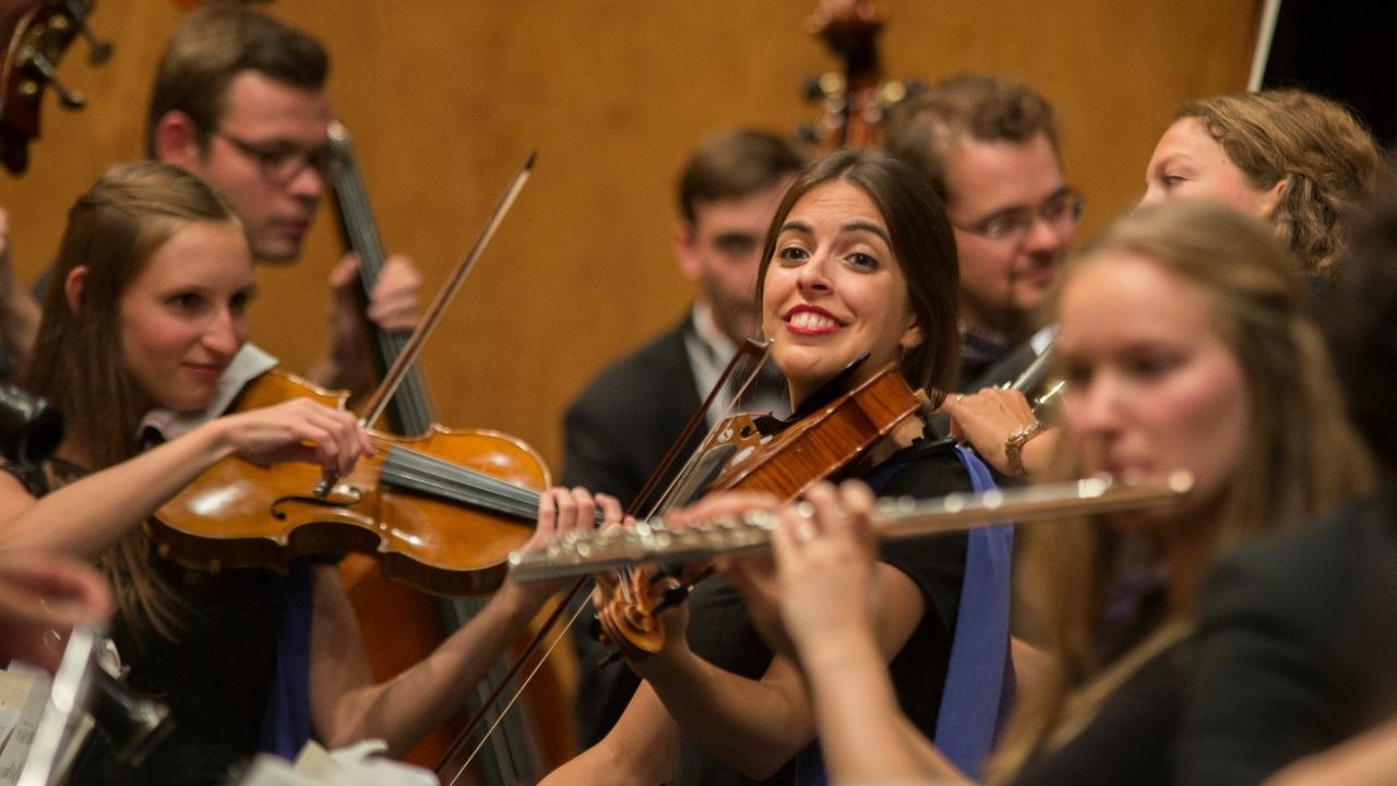 Viele junge Musikerinnen und Musiker sitzen in den Orchesterreihen.