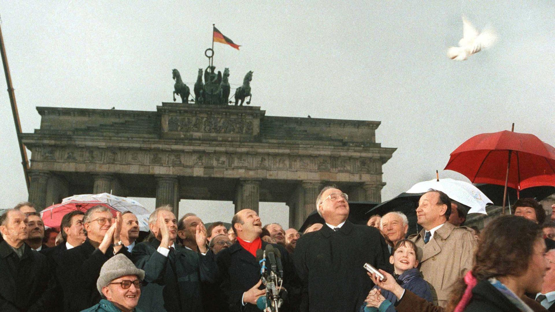 28 Jahre nach dem Mauerbau ist das Brandenburger Tor wieder zugänglich: DDR-Ministerpräsident Hans Modrow und Bundeskanzler Helmut Kohl lassen am 22. Dezember 1989 Friedenstauben aufsteigen. In der Mitte Walter Momper, Regierender Bürgermeister von Berlin.