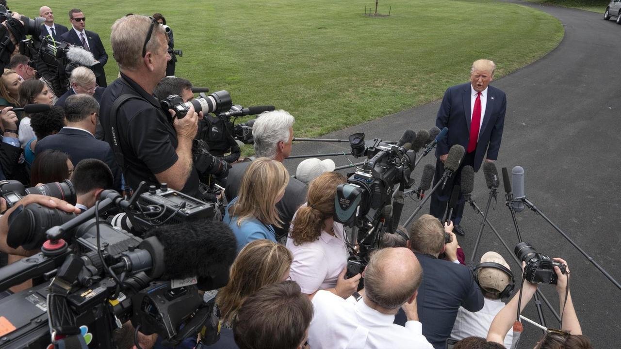 US-Präsident Trump steht vor einer Menschentraube von Journalisten auf einer Straße im Garten des Weißen Hauses. Die Reporter filmen und halten ihm Mikrofone entgegen.