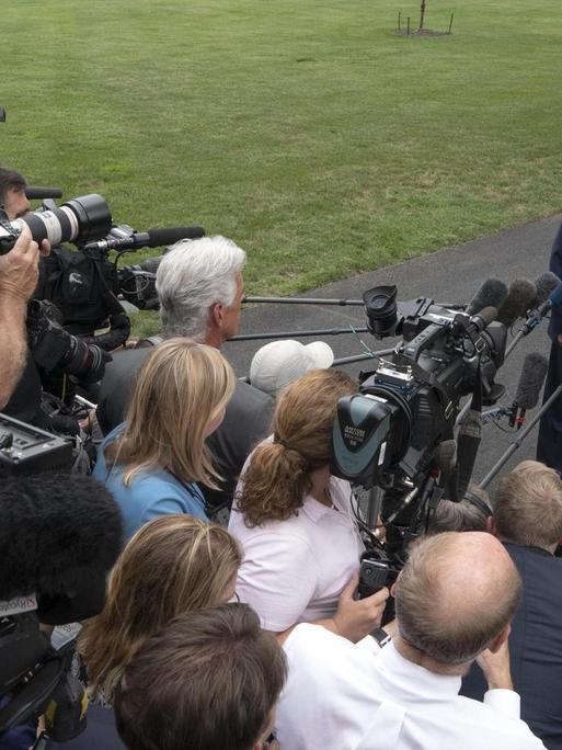 US-Präsident Trump steht vor einer Menschentraube von Journalisten auf einer Straße im Garten des Weißen Hauses. Die Reporter filmen und halten ihm Mikrofone entgegen.