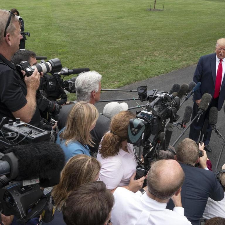US-Präsident Trump steht vor einer Menschentraube von Journalisten auf einer Straße im Garten des Weißen Hauses. Die Reporter filmen und halten ihm Mikrofone entgegen.
