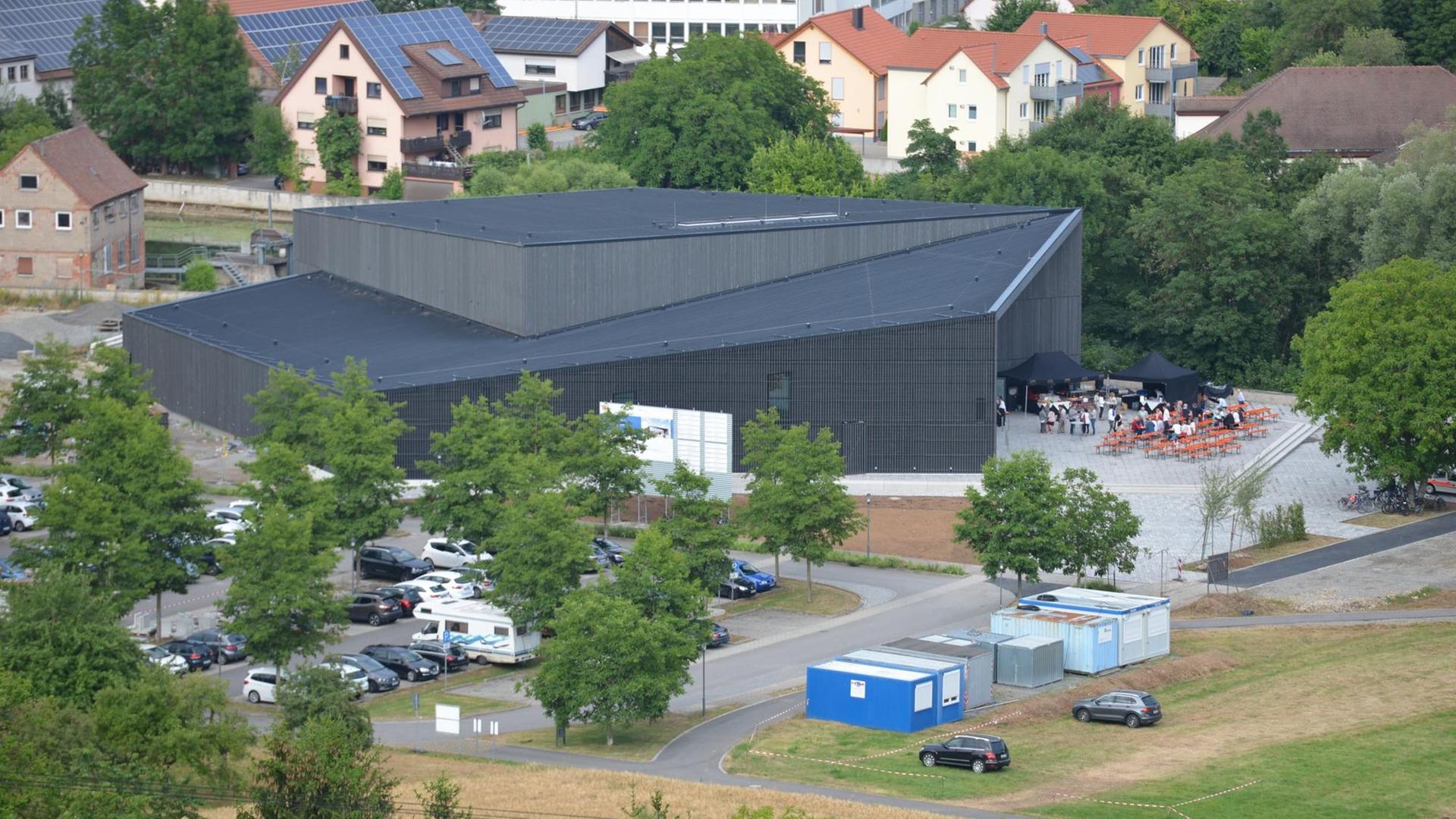 Das Bild zeigt die Tauberphilharmonie umgeben von Wohnhäusern und einem Parkplatz