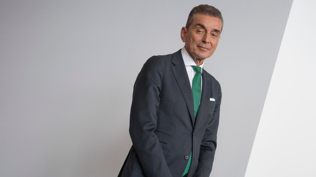 Der Publizist und Jurist Michel Friedman lächelt im Anzug und grüner Krawatte in die Kamera.
