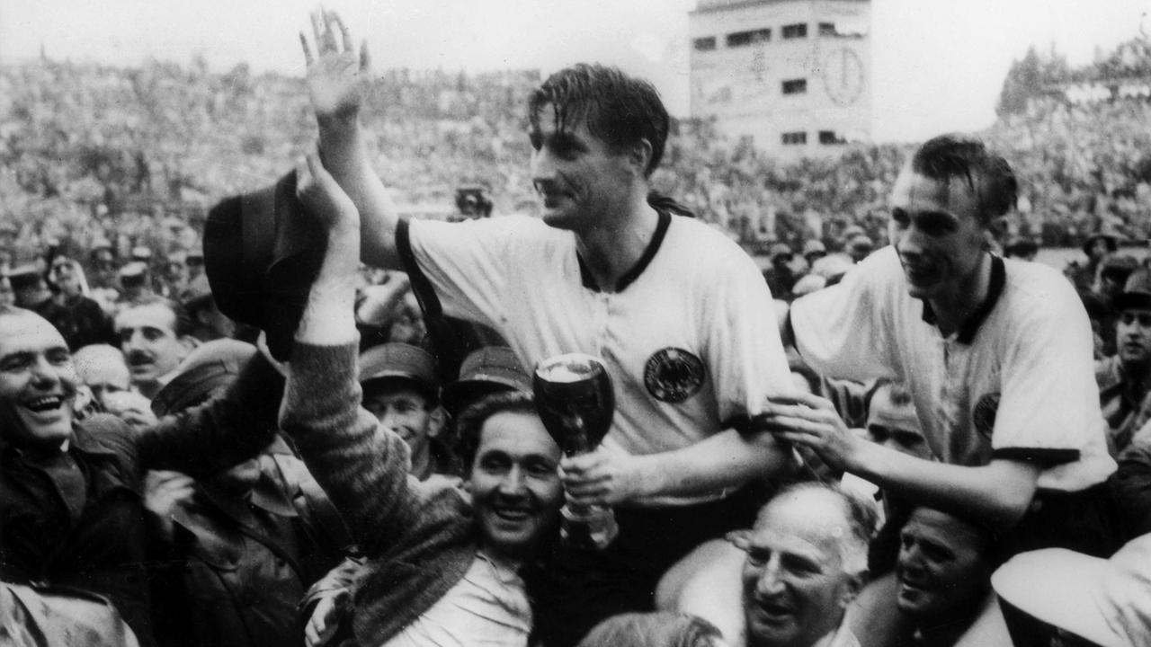 Die deutschen Fußballspieler Fritz Walter (M, mit dem Pokal in denHänden) und Horst Eckel (r) werden am 4.7.1954 von Fans frenetisch gefeiertund auf den Schultern durch das Stadion getragen.