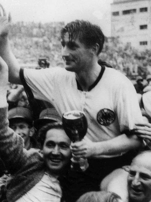 Die deutschen Fußballspieler Fritz Walter (M, mit dem Pokal in den Händen) und Horst Eckel (r) werden am 4.7.1954 von Fans frenetisch gefeiert und auf den Schultern durch das Stadion getragen.