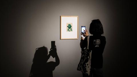 Eine Frau macht mit ihrem Smartphone ein Foto von einem Kunstobjekt