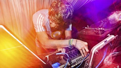 Ein DJ an einem Mischpult in einem Club.