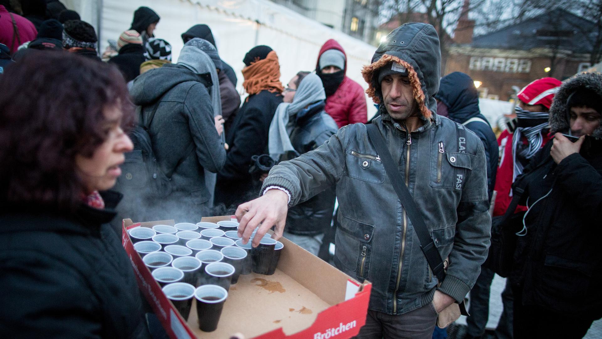 Helfer versorgen wartende Flüchtlinge vor dem Landesamt für Gesundheit und Soziales in Berlin bei frostigen Temperaturen mit Heißgetränken. In dem Amt in Berlins Turmstraße können Flüchtlinge sich registrieren lassen oder erste Unterstützungsleistungen erhalten. Aufnahme vom 4. Januar 2016