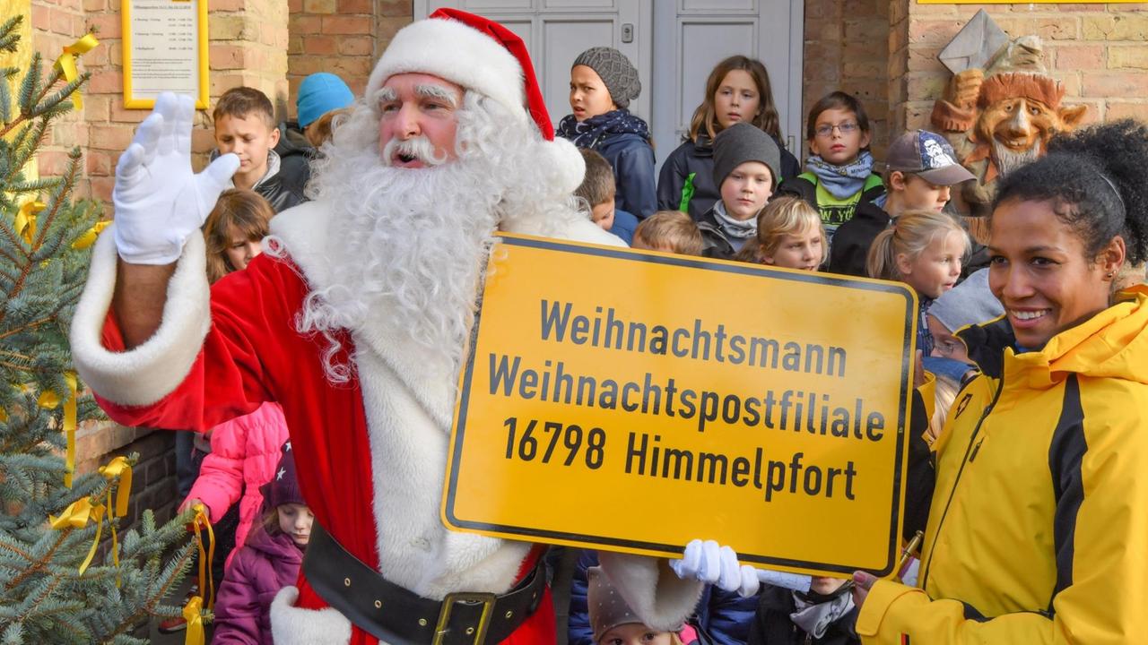 Mariama Jamanka, Olympiasiegerin 2018 im Zweierbob, und der Weihnachtsmann zeigen die Adresse der Weihnachtspostfiliale in Himmelspfort.