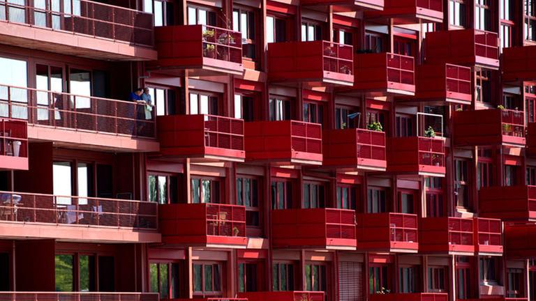 Ein rotes Mietshaus mit vielen Balkonen.