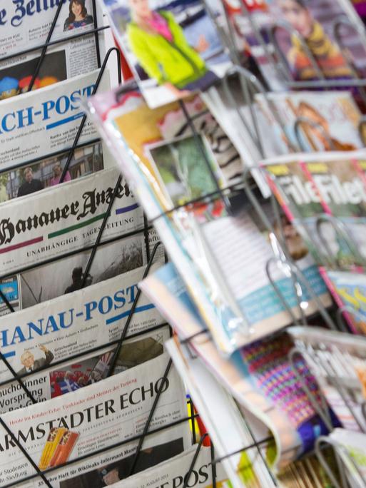 Tageszeitungen stecken an einem Zeitungsstand in Drehständern.