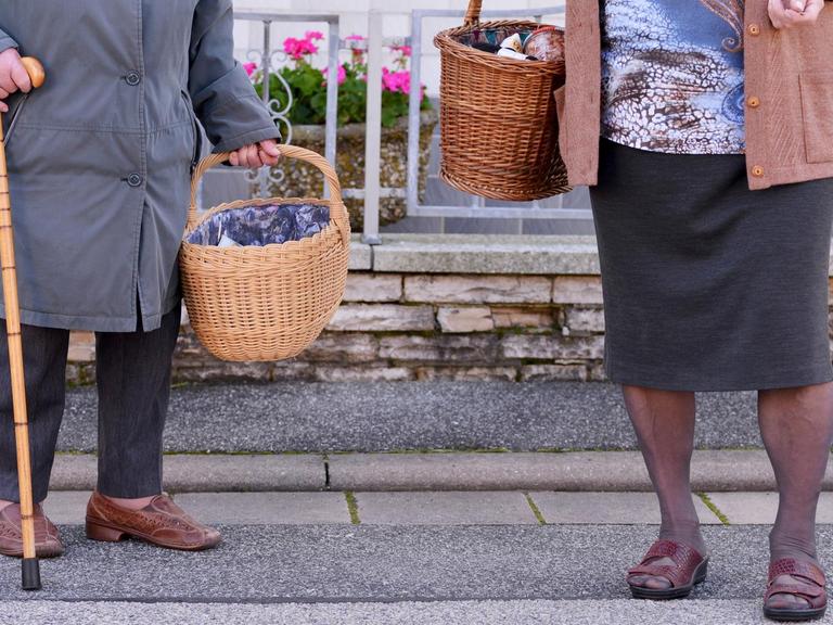 Zwei ältere Dame tragen nach einem Einkauf ihre Lebensmittel nach Hause.