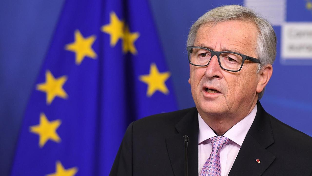EU-Kommissionschef Jean-Claude Juncker steht neben einer Europa-Fahne-