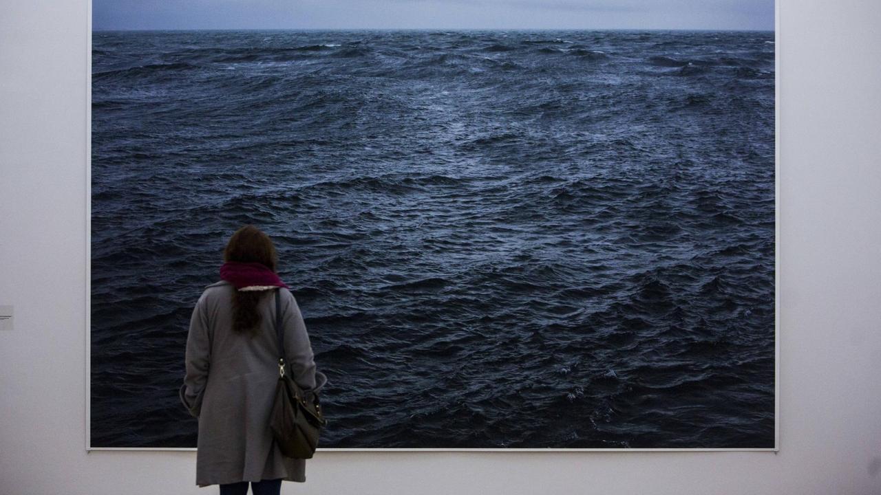 Ausstellungsbesucherin vor einem Werk des Fotografen Wolfgang Tillmans, auf dem das Meer zu sehen ist