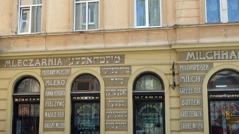 Ein alte Beschriftung, liebevoll nachgemalt, an einer Hauswand in Lemberg: Neben dem polnischen "Mleczarnia" und dem deutschen "Milchhalle" stehen hebräische Zeichen.