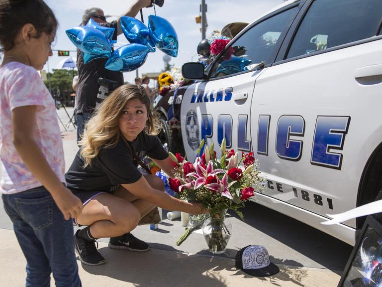 Eine Frau und ihre Tochter legen in Dallas Blumen an einem Polizeiauto nieder, um der getöteten Polizisten zu gedenken