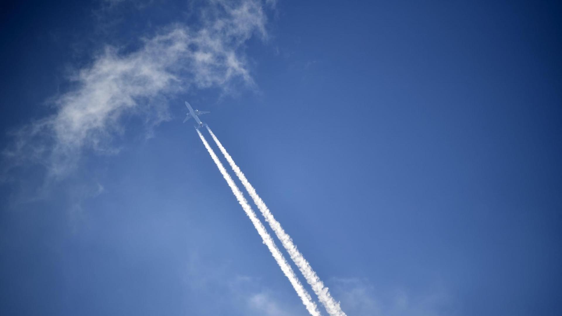 Blauer Himmel mit einem Flugzeug mit Kondensstreifen.