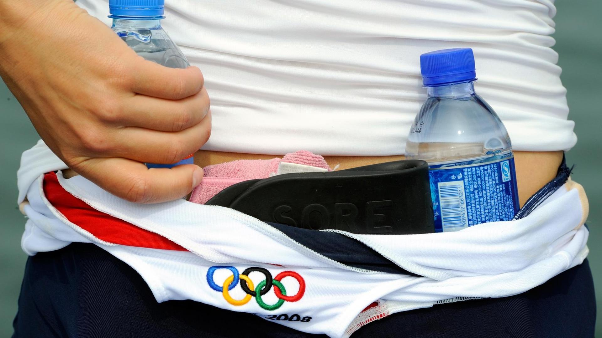 Eine Ruderin aus den USA trägt am Mittwoch (30.07.2008) in Peking auf der Ruderstrecke im Olympia-Park Wasserflaschen in ihrem Trikot.