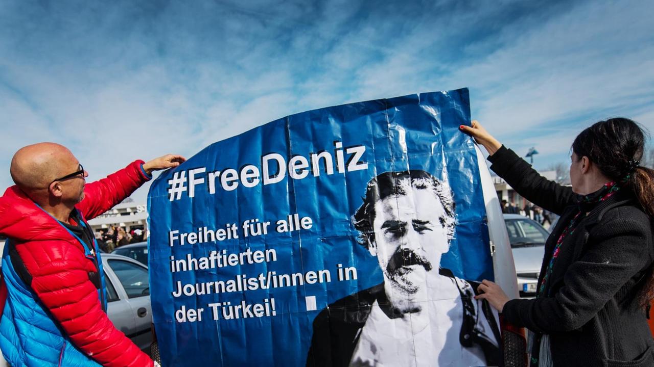 Zwei Demonstranten halten ein Plakat hoch, um für die Freilassung des in der Türkei inhaftierten Journalisten Deniz Yücel zu werben.