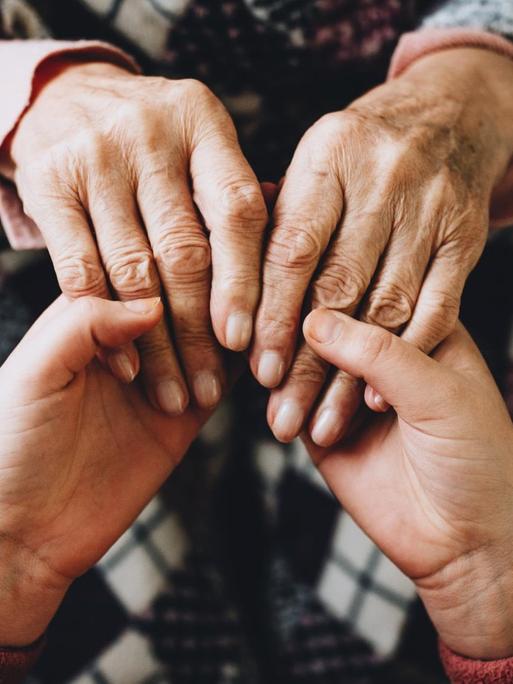 Junge und alte Hände halten sich, Großmutter und Enkelkind.