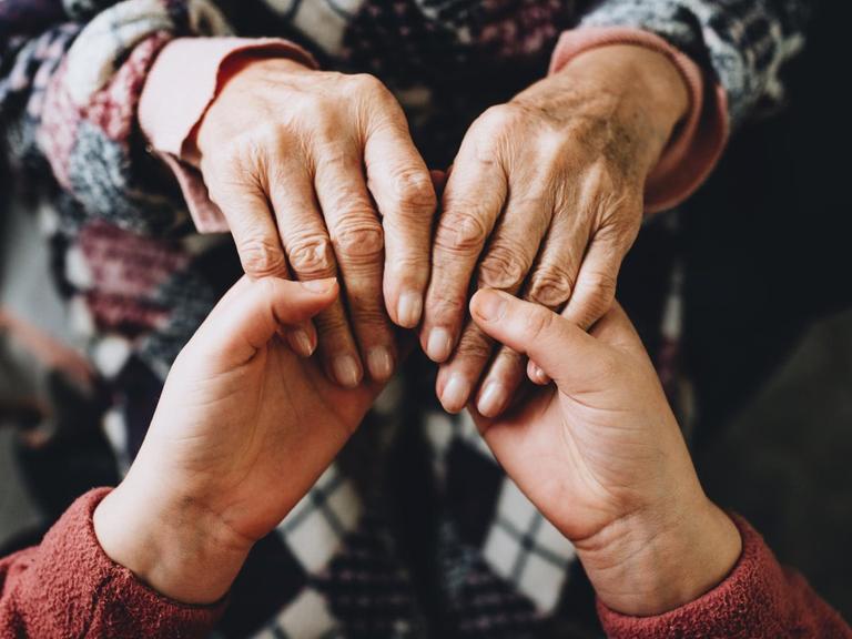 Junge und alte Hände halten sich, Großmutter und Enkelkind.