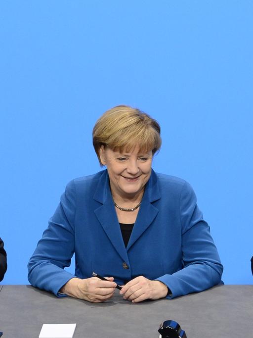 Der SPD-Vorsitzende Sigmar Gabriel, Bundeskanzlerin Angela Merkel (CDU) und CSU-Chef Horst Seehofer sitzen an einem Tisch und unterzeichnen den Koalitionsvertrag.