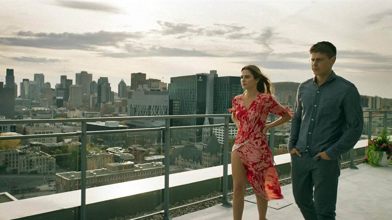 Ein Mann und eine Frau gehen auf einer Dachterasse vor der New Yorker Skyline