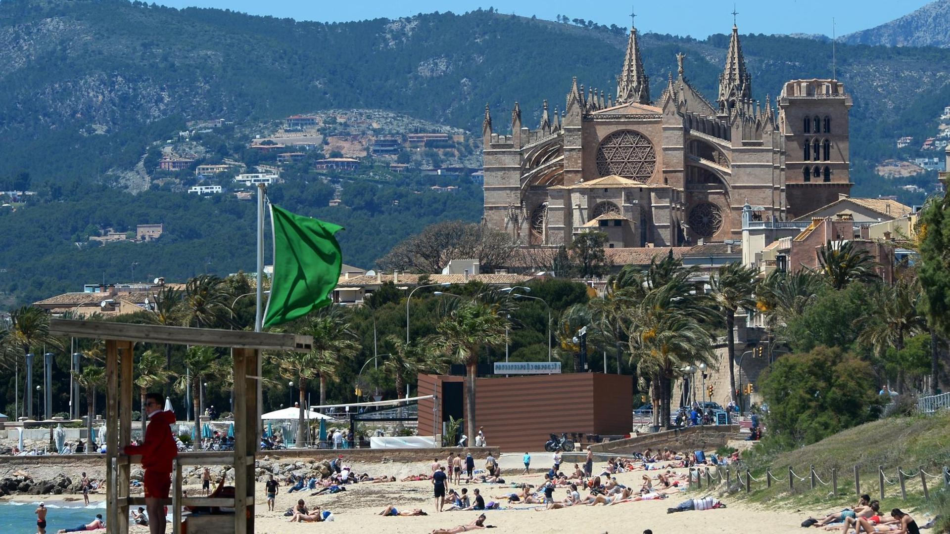 Der Strand von Es Portixol und die Kathedrale der Heiligen Maria in Palma de Mallorca auf Mallorca (Spanien).
