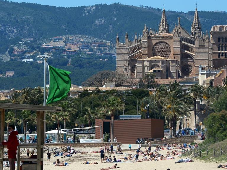 Der Strand von Es Portixol und die Kathedrale der Heiligen Maria in Palma de Mallorca auf Mallorca (Spanien).