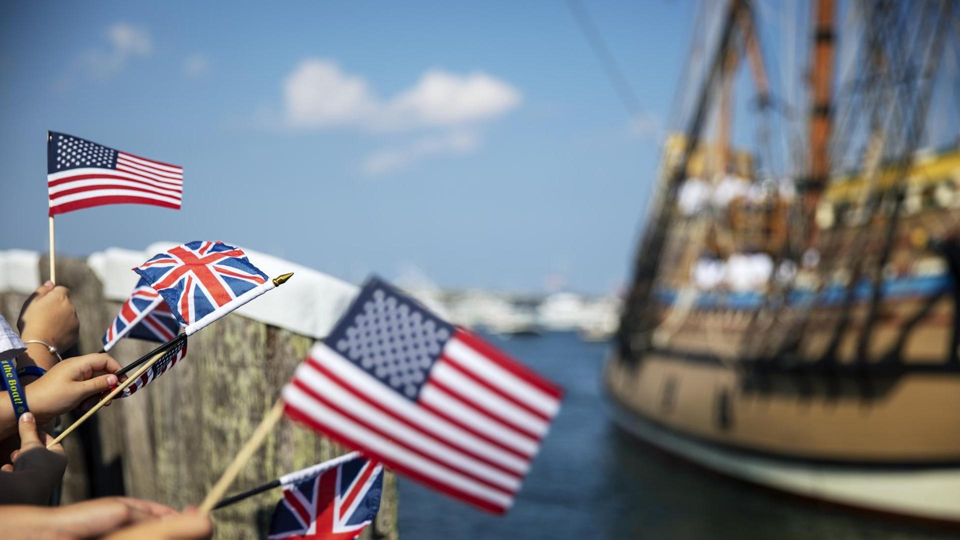 Eine Menge schwenkt Flaggen der USA und Großbritanniens beim Einlauf der Mayflower-Rekonstruktion in den Hafen von Plymouth.