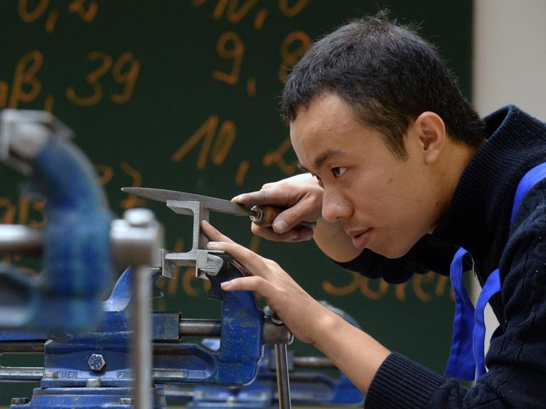 Thai Minh Nguyen aus Vietnam bearbeitet in der Metallwerkstatt des Bildungswerks der Sächsischen Wirtschaft ein Metallteil.