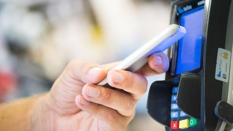 Ein Mann bezahlt in einem Laden in Berlin mit seinem Smartphone.