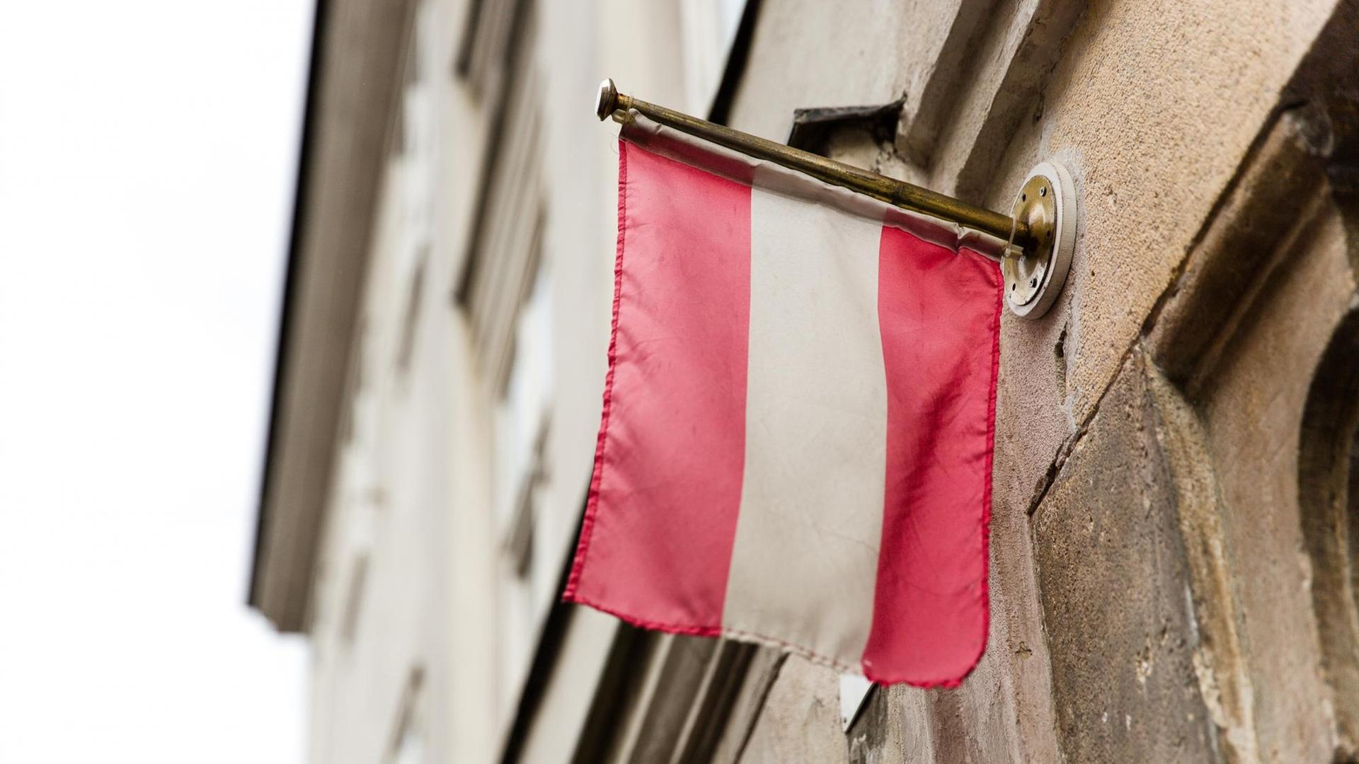 Die Flagge von Österreich hängt an einer Hauswand.