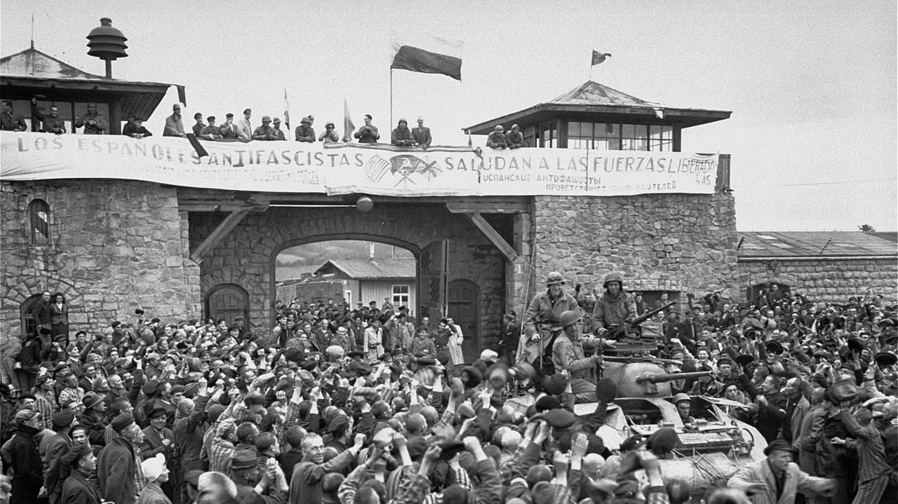 Überlebende Häftlinge jubeln vermutlich am 7. Mai 1945 in einer nachgestellten Szene anläßlich Ihrer Befreiung amerikanischen Soldaten der Elften Panzerdivision zu.