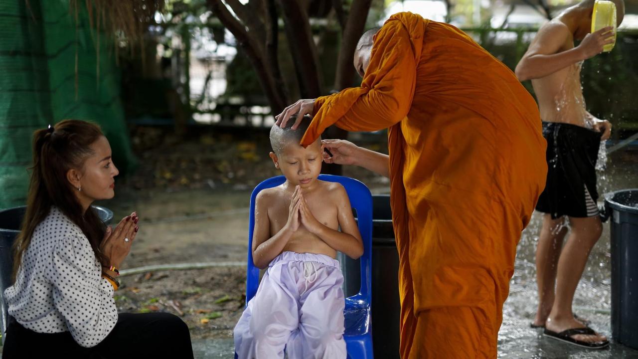 Zu Ehren Königs Bhumibols fand nach dessen Tod eine Massenordination statt. Hier wird einem Jungen im Beisein der Mutter von einem buddhistischen Mönch der Kopf rasiert.