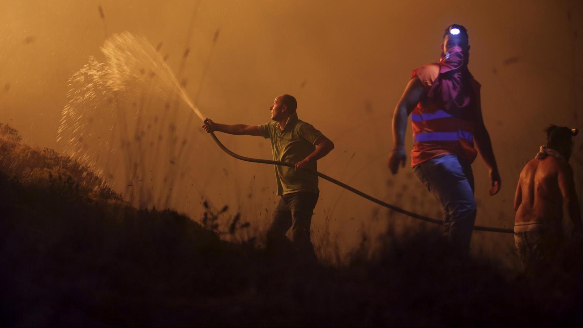 Freiwillige Helfer versuchen am 16.10.2017 in Obidos (Portugal) mit einem Wasserschlauch ein Feuer zu löschen.