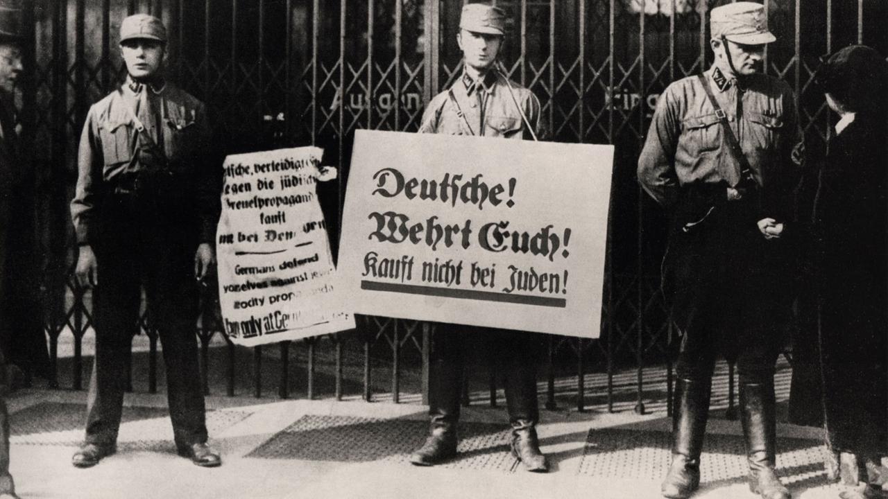 Durchführung des angeordneten Boykotts gegen jüdische Einrichtungen. SA mit Plakaten vor einem jüdischen Geschäft.