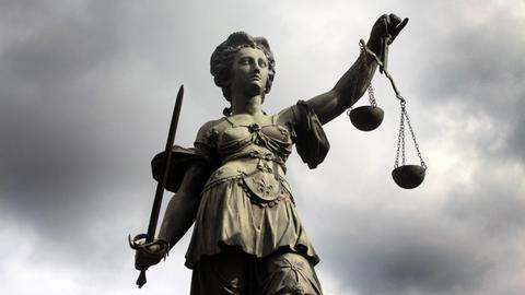 Eine Statue der Justitia vor grauem Himmel