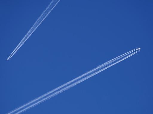 Zwei Flugzeuge mit Kondensstreifen am blauen Himmel.