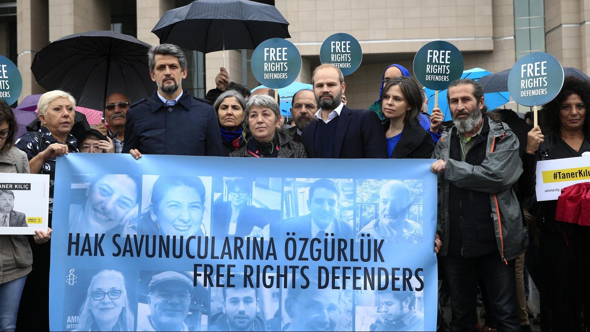 Menschenrechts-Aktivisten demonstrieren am 25.10.2017 vor einem Gericht in Istanbul (Türkei) mit einem Transparent mit Bildern der Angeklagten gegen den Prozess gegen elf Menschenrechtler, darunter auch der Deutsche Peter Steudtner (auf dem Banner der 2.v.r. unten).
