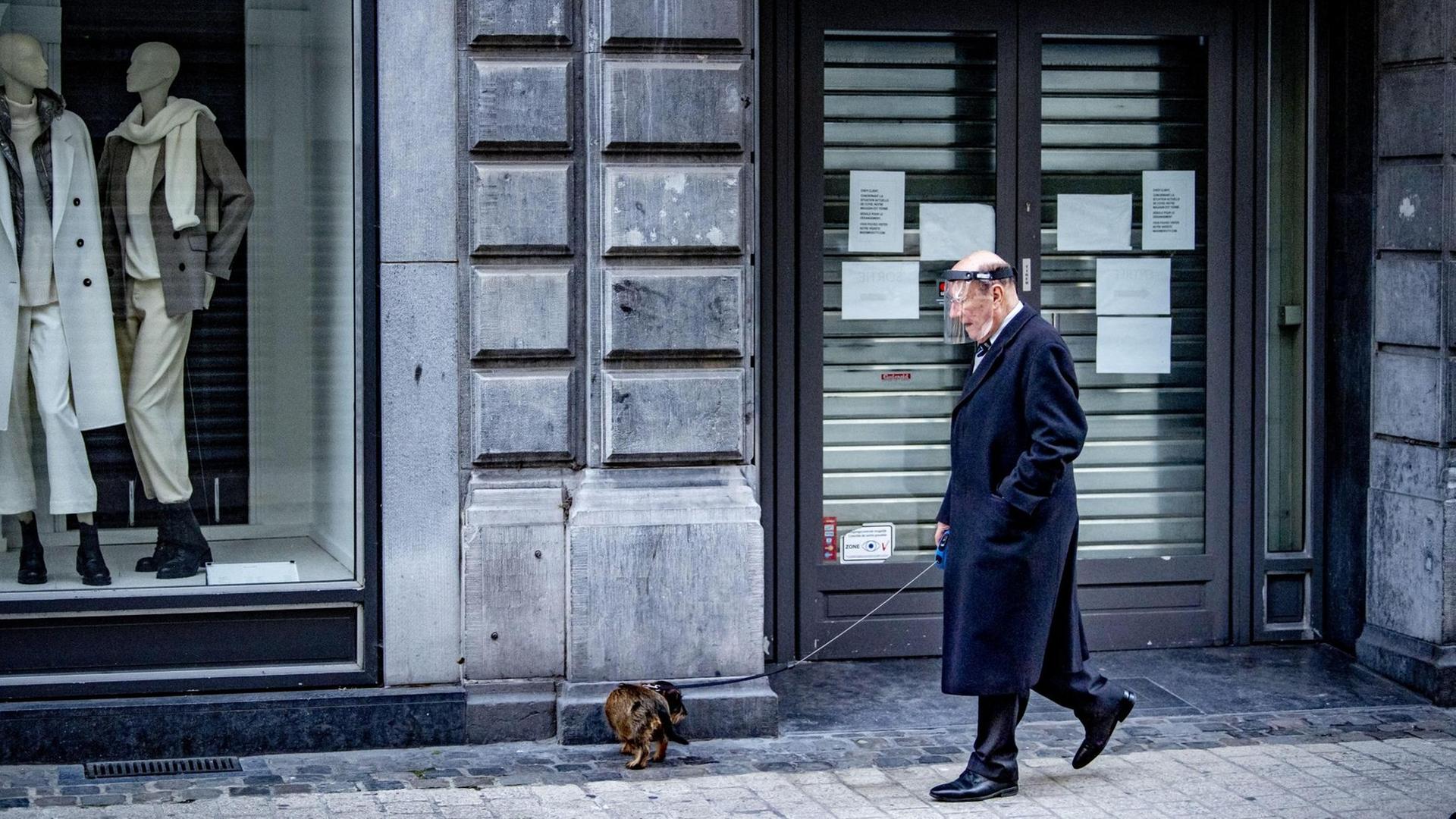 Ein alter Mann geht während des Lockdowns mit seinem Hund in Lüttich spazieren.