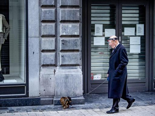 Ein alter Mann geht während des Lockdowns mit seinem Hund in Lüttich spazieren.